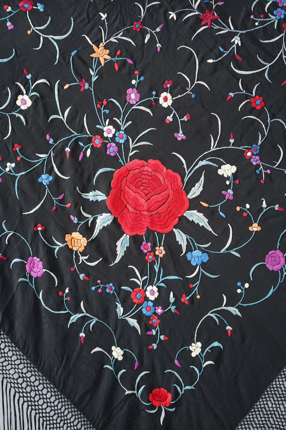 A late 19th century Chinese black silk polychrome floral embroidered shawl with long silk fringing. Embroidered with large red roses and an all over multi coloured floral sprig design. 123cm x 108cm. Condition, silk and